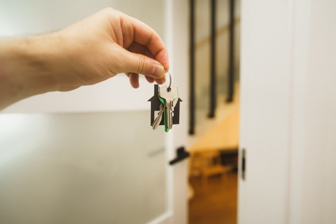 A close-up shot of two distinct sets of house keys lying side-by-side on a wooden table, representing the choice between two different real estate paths.