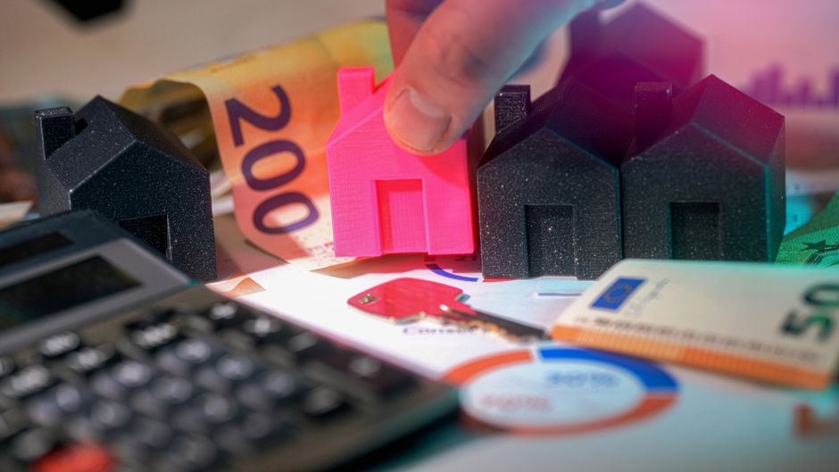 A close-up shot of a person's hands, one holding a set of house keys and the other on a calculator, symbolizing the financial anxiety of a home purchase.