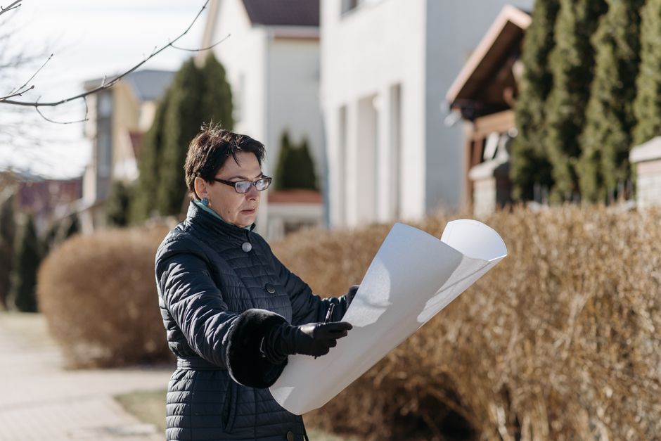 A person stands on the sidewalk looking at a suburban house with an expression of worry and uncertainty, illustrating the mental doubts that can occur when buying a home.